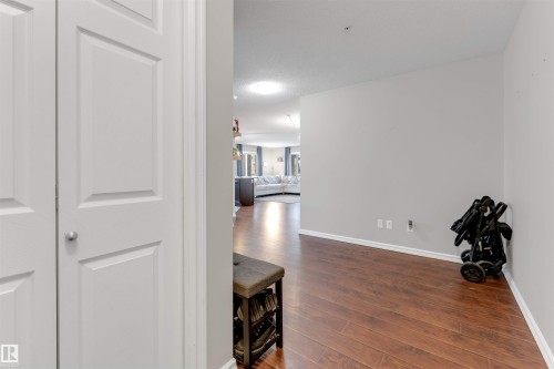 Hardwood-finish flooring throughout, complemented by light gray wall paint and white trim - 201 4403 23 Street, Edmonton, AB - Indoor Photo Showing Other Room