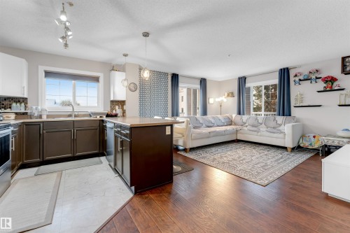 Open-concept living space with dark wood-finish flooring extending into the seating area - 201 4403 23 Street, Edmonton, AB - Indoor