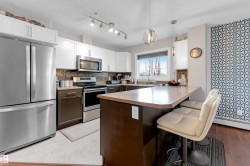 Contemporary kitchen featuring stainless steel appliances, white upper cabinetry, and dark lower cabinetry - 
