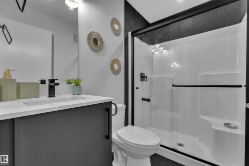Contemporary bathroom featuring a dark gray vanity with a white countertop, an integrated rectangular sink, and a matte black faucet - 5722 Kootook Way, Edmonton, AB - Indoor Photo Showing Bathroom