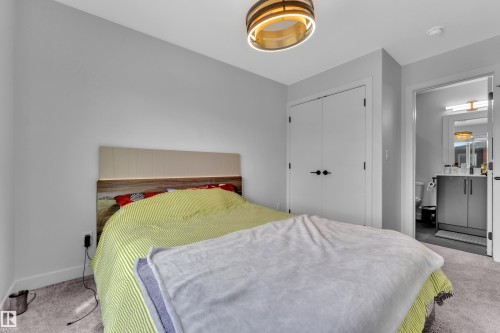Bedroom featuring carpet flooring, a built-in closet with double doors, and a contemporary ceiling fixture - 5722 Kootook Way, Edmonton, AB - Indoor Photo Showing Bedroom