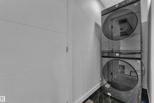 Stacked washer and dryer unit with a dark finish - 5722 Kootook Way, Edmonton, AB - Indoor Photo Showing Laundry Room