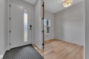 Foyer featuring a modern white entry door with frosted glass insert, wood-finish flooring, a contemporary ceiling light fixture, and a single window - 5722 Kootook Way, Edmonton, AB  - Indoor Photo Showing Other Room 