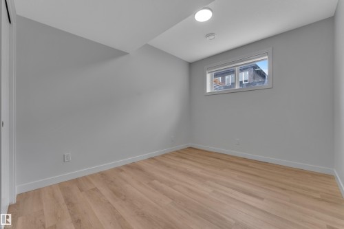Room featuring wood-finish flooring, light gray walls, white baseboards, and a window with white trim - 5722 Kootook Way, Edmonton, AB - Indoor Photo Showing Other Room