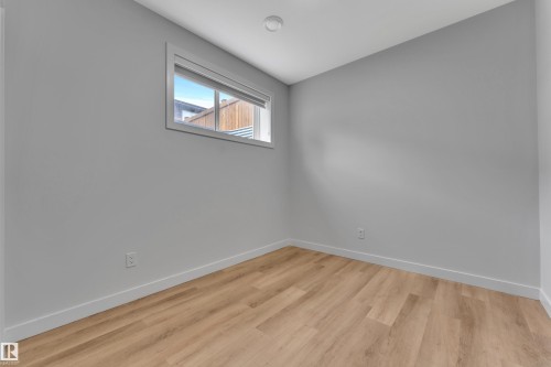 Neutral tone walls with wood-finish flooring, a contemporary window featuring a roller shade, and recessed ceiling lighting - 5722 Kootook Way, Edmonton, AB - Indoor Photo Showing Other Room