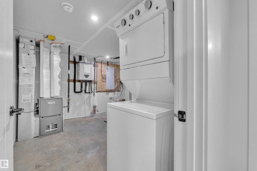Dedicated laundry area featuring a stackable washer and dryer unit, a forced-air furnace, and a water heater - 5722 Kootook Way, Edmonton, AB - Indoor Photo Showing Laundry Room