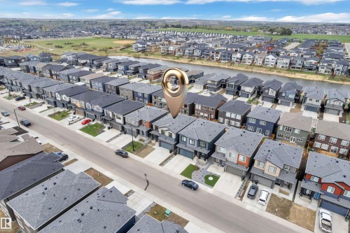 Modern residential community featuring a variety of detached homes with attached garages, paved driveways, and manicured front lawns - 5722 Kootook Way, Edmonton, AB - Outdoor With View