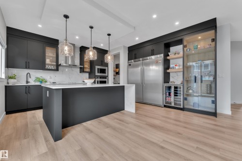 Modern kitchen featuring dark cabinetry, a large center island with a white countertop, and stainless steel appliances - 5722 Kootook Way, Edmonton, AB - Indoor Photo Showing Kitchen With Upgraded Kitchen