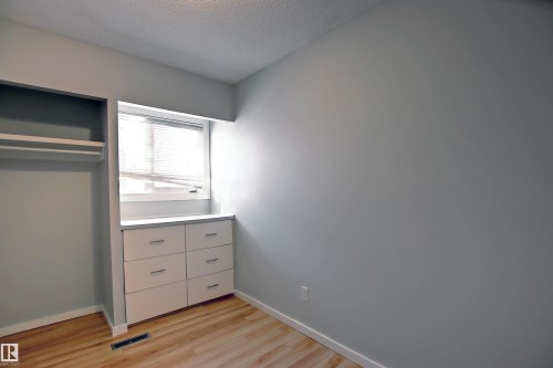 Room featuring wood-finish flooring, light gray wall paint, and a built-in storage unit with six drawers - 11 14120 80 Street, Edmonton, AB - Indoor
