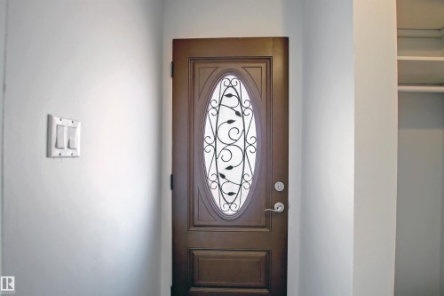 Oval-paneled entry door with decorative ironwork - 11 14120 80 Street, Edmonton, AB - Indoor Photo Showing Other Room