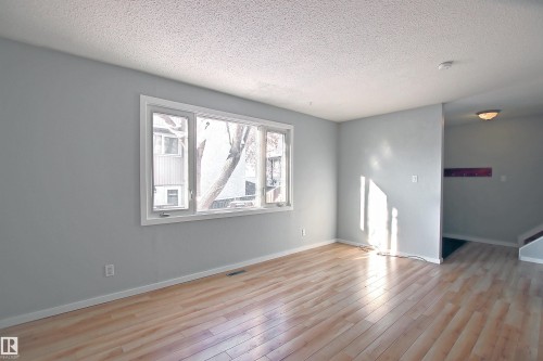 Spacious room featuring light wood-finish flooring and a large multi-pane window - 11 14120 80 Street, Edmonton, AB - Indoor Photo Showing Other Room