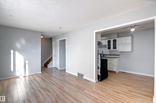 Light wood-finish flooring extending through an open doorway to a kitchen area - 11 14120 80 Street, Edmonton, AB - Indoor Photo Showing Other Room