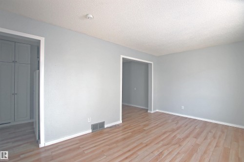 Spacious room featuring light wood-finish flooring, light gray wall finishes, and white trim - 11 14120 80 Street, Edmonton, AB - Indoor Photo Showing Other Room