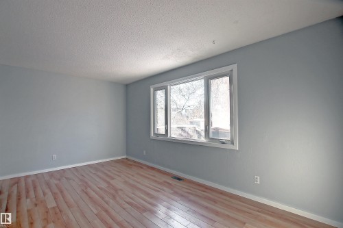 Bright interior space featuring a multi-pane window with white trim, light-toned wood-finish flooring, light gray walls, and white baseboards - 11 14120 80 Street, Edmonton, AB - Indoor Photo Showing Other Room