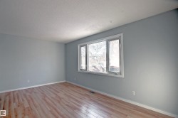 Bright interior space featuring a multi-pane window with white trim, light-toned wood-finish flooring, light gray walls, and white baseboards - 