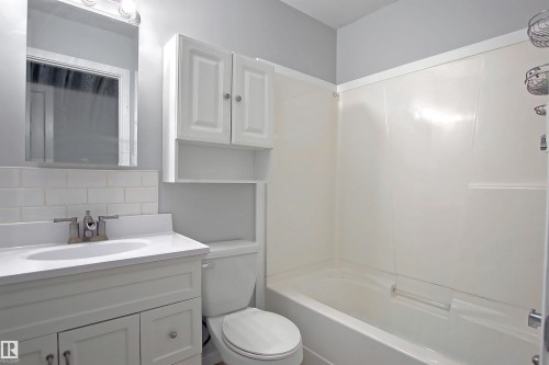 Full bathroom featuring a white vanity with an integrated sink, subway tile backsplash, and a shower/tub combination - 11 14120 80 Street, Edmonton, AB - Indoor Photo Showing Bathroom