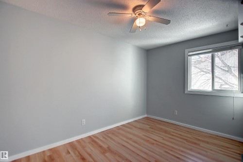 Light wood-finish flooring complemented by neutral grey wall paint - 11 14120 80 Street, Edmonton, AB - Indoor Photo Showing Other Room