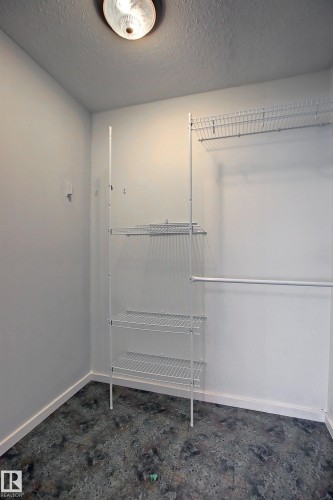 Dedicated closet space featuring a ceiling-mounted light fixture, white wire shelving units, and a hanging rod - 11 14120 80 Street, Edmonton, AB - Indoor