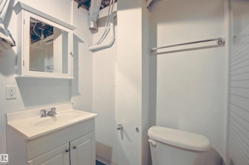 Bathroom featuring a white vanity with integrated sink, chrome faucet, wall-mounted medicine cabinet, toilet, and towel bar - 11 14120 80 Street, Edmonton, AB - Indoor Photo Showing Bathroom