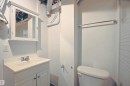 Bathroom featuring a white vanity with integrated sink, chrome faucet, wall-mounted medicine cabinet, toilet, and towel bar - 11 14120 80 Street, Edmonton, AB  - Indoor Photo Showing Bathroom 