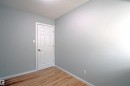 Interior room featuring wood-finish flooring, light gray wall paint, white baseboards, and a white six-panel interior door with chrome hardware - 11 14120 80 Street, Edmonton, AB  - Indoor Photo Showing Other Room 