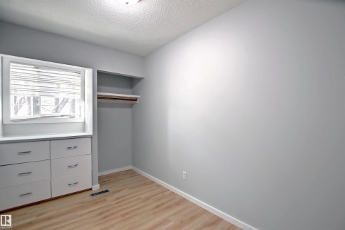 Room featuring wood-finish flooring, light grey walls, and a recessed window with blinds - 11 14120 80 Street, Edmonton, AB - Indoor Photo Showing Other Room