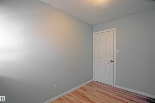 Light gray wall paint with white baseboards and wood-finish flooring - 11 14120 80 Street, Edmonton, AB - Indoor Photo Showing Other Room