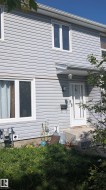 Light gray vinyl siding exterior with white window frames and a storm door - 