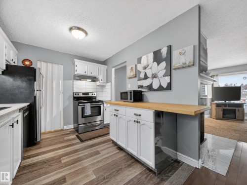 Kitchen featuring wood-finish flooring, white cabinetry, and stainless steel appliances - 165 2703 79 Street, Edmonton, AB - Indoor Photo Showing Kitchen