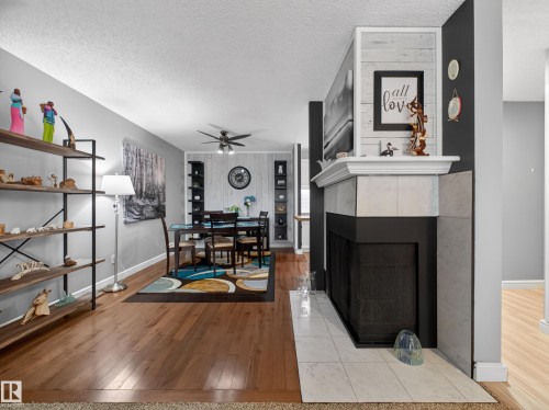 Tiled fireplace with a white mantel, wood-finish flooring, and light gray wall paint - 165 2703 79 Street, Edmonton, AB - Indoor With Fireplace
