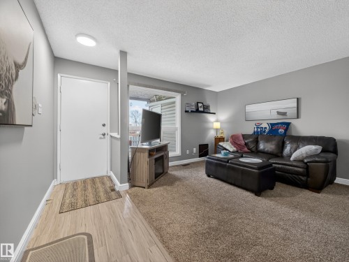 Living area featuring light wood-finish flooring transitioning to neutral-toned carpet - 165 2703 79 Street, Edmonton, AB - Indoor