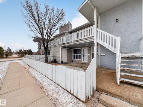 Multi-level townhouse exterior featuring light-colored siding and a white picket fence - 165 2703 79 Street, Edmonton, AB - Outdoor