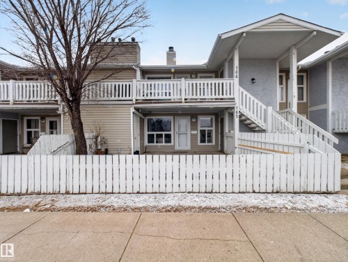 Multi-level property featuring a white picket fence, covered entrance, exterior staircase, and upper-level balconies with white railings - 165 2703 79 Street, Edmonton, AB - Outdoor
