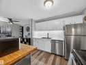 Kitchen featuring white cabinetry, stainless steel appliances, white subway tile backsplash, and wood-finish flooring - 165 2703 79 Street, Edmonton, AB  - Indoor Photo Showing Kitchen With Double Sink 