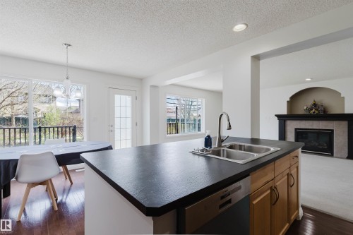Kitchen island with a double basin stainless steel sink, pull-down faucet, and integrated dishwasher - 1951 120 Street, Edmonton, AB - Indoor