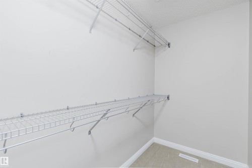 Closet interior with white wire shelving, hanging rods, and light-colored carpeting - 1951 120 Street, Edmonton, AB - Indoor With Storage