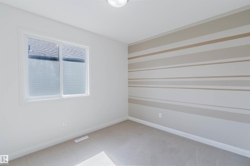 Carpeted room featuring a horizontal striped accent wall and a window with blinds - 1951 120 Street, Edmonton, AB - Indoor Photo Showing Other Room