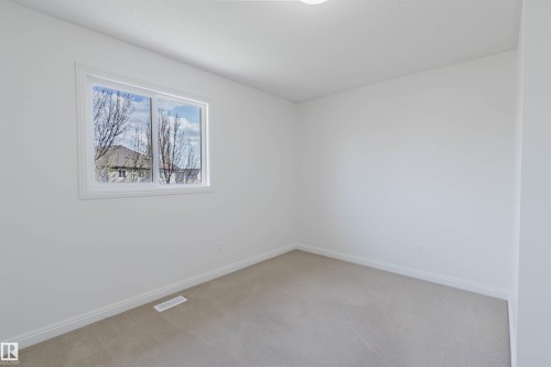 Bright interior space featuring a window with white trim, light-colored carpeting, white baseboards, and neutral wall finishes - 1951 120 Street, Edmonton, AB - Indoor Photo Showing Other Room
