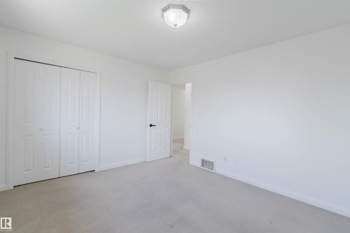 Neutral-toned carpeting extends throughout this room, featuring white walls and a white ceiling with a flush-mount light fixture - 1951 120 Street, Edmonton, AB - Indoor Photo Showing Other Room