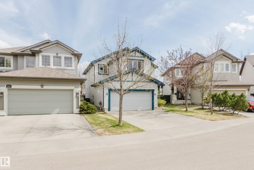 Contemporary suburban residence featuring a two-car garage, concrete driveway, and light grey siding - 1951 120 Street, Edmonton, AB - Outdoor With Facade