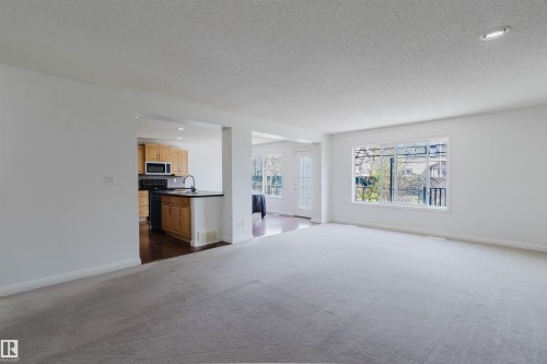 Spacious living area featuring light gray carpeting and white walls - 1951 120 Street, Edmonton, AB - Indoor