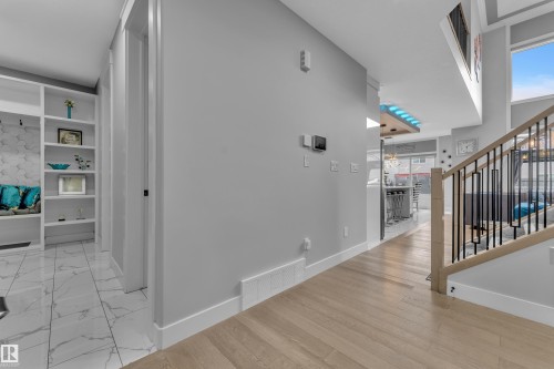Expansive entryway featuring wood-finish flooring, a modern staircase with dark metal spindles and a light wood handrail, and high ceilings with upper-level windows - 8025 174A Avenue, Edmonton, AB - Indoor Photo Showing Other Room