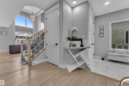Two-story foyer featuring light wood-finish flooring, a contemporary staircase with wood and wrought iron railings, and a prominent two-story window - 8025 174A Avenue, Edmonton, AB - Indoor Photo Showing Other Room