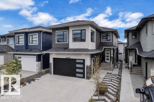 Modern two-story residence with a multi-tone exterior, dark framed windows, and a black garage door with frosted glass panels - 8025 174A Avenue, Edmonton, AB - Outdoor With Facade