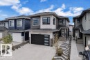Modern two-story residence with a multi-tone exterior, dark framed windows, and a black garage door with frosted glass panels - 8025 174A Avenue, Edmonton, AB  - Outdoor With Facade 