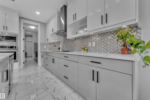 Contemporary kitchen featuring two-tone cabinetry, white countertops, and a herringbone tile backsplash - 8025 174A Avenue, Edmonton, AB - Indoor Photo Showing Kitchen With Upgraded Kitchen