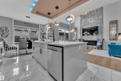 Modern kitchen island with integrated dishwasher, white countertop, and contemporary pendant lighting - 8025 174A Avenue, Edmonton, AB - Indoor Photo Showing Kitchen With Upgraded Kitchen