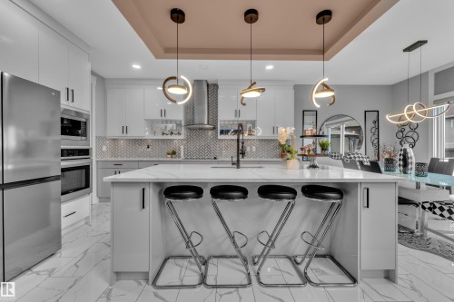 Kitchen island featuring a white countertop and seating for three - 8025 174A Avenue, Edmonton, AB - Indoor Photo Showing Kitchen With Upgraded Kitchen