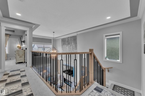 Upper-level landing featuring a wood handrail with contemporary black balusters, recessed lighting, and tray ceiling detail - 8025 174A Avenue, Edmonton, AB -  Photo Showing Other Room