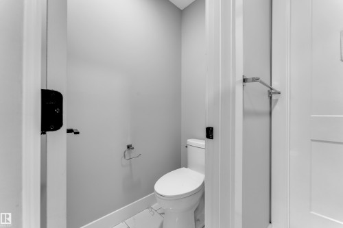 Modern powder room featuring a white toilet, light gray walls, and white tile flooring - 8025 174A Avenue, Edmonton, AB - Indoor Photo Showing Bathroom